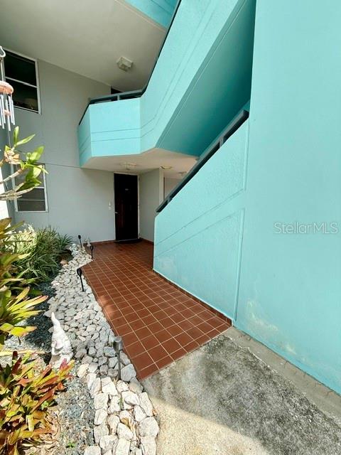An exterior view shows a turquoise building with a tiled walkway leading to a dark door — 457 CHALETS DE LA PLAYA UNIT 457, VEGA BAJA, PR