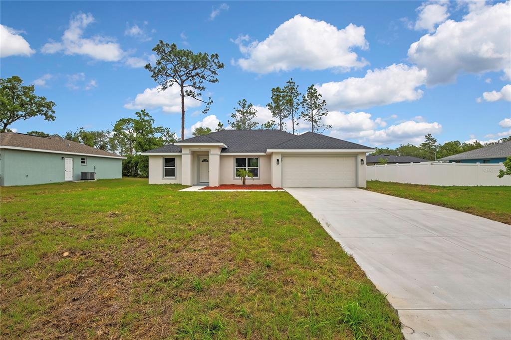 A single-story house with a beige exterior, a two-car garage, and a concrete driveway — 3261 W VIKING LANE, CITRUS SPRINGS, FL