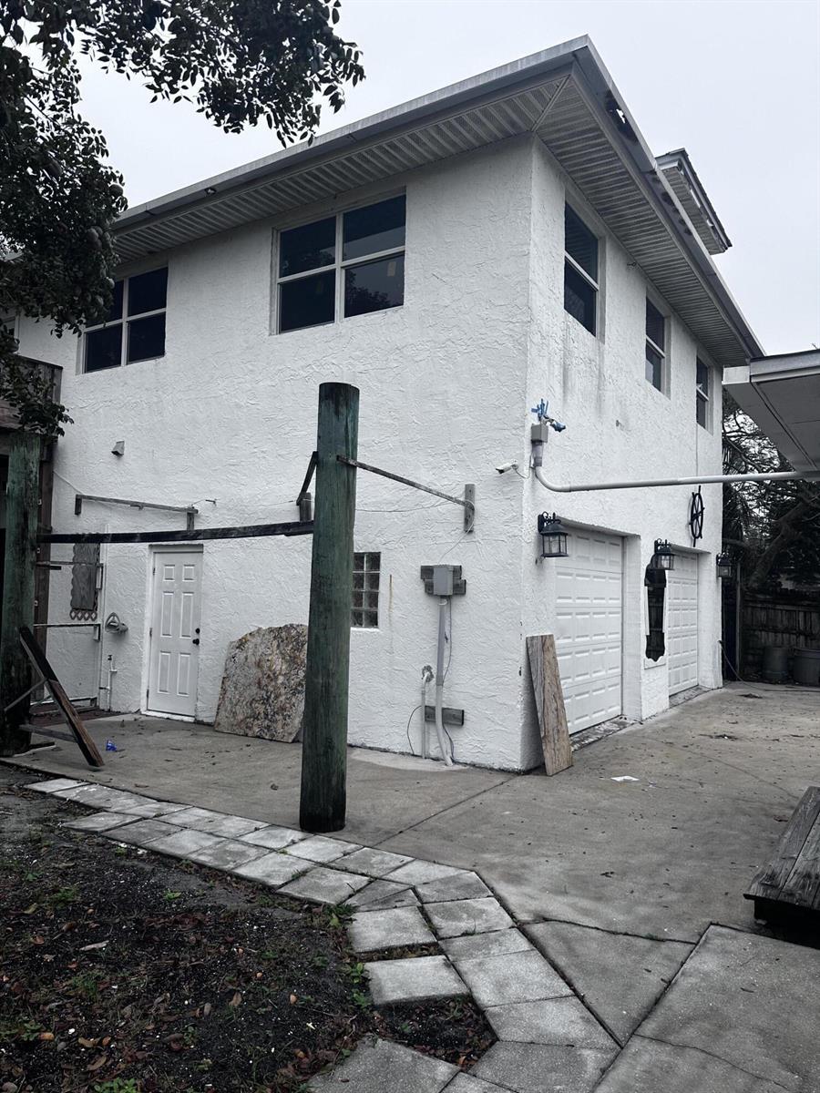 A two-story white stucco building features a garage with two doors and a side entrance — 130 NE 4th Avenue, Boynton Beach FL 33435, BOYNTON BEACH, FL