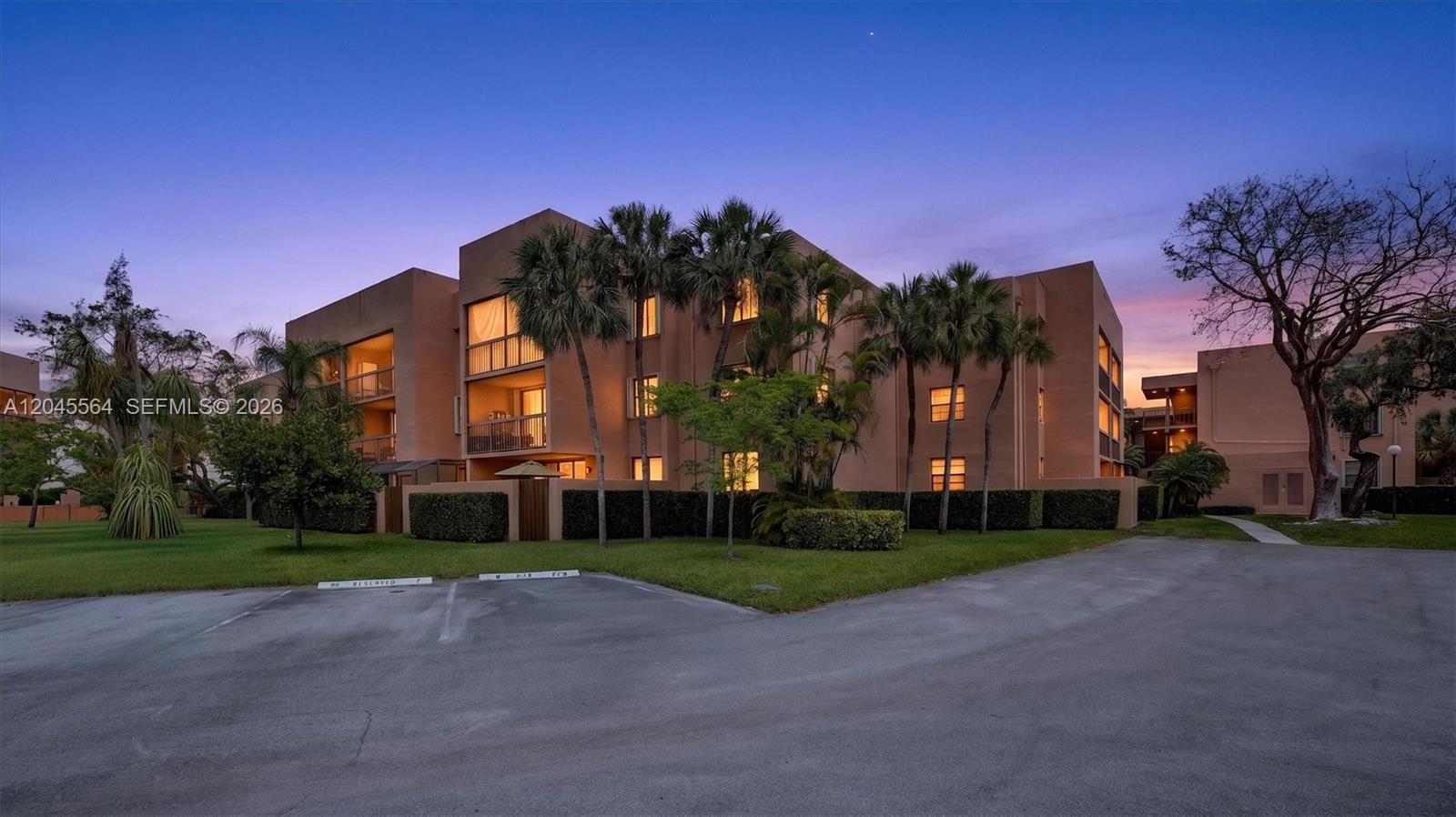 A multi-story tan apartment building is surrounded by palm trees and a paved parking lot — 10975 SW 107th ST. # 202, Kendall FL 33176, KENDALL, FL