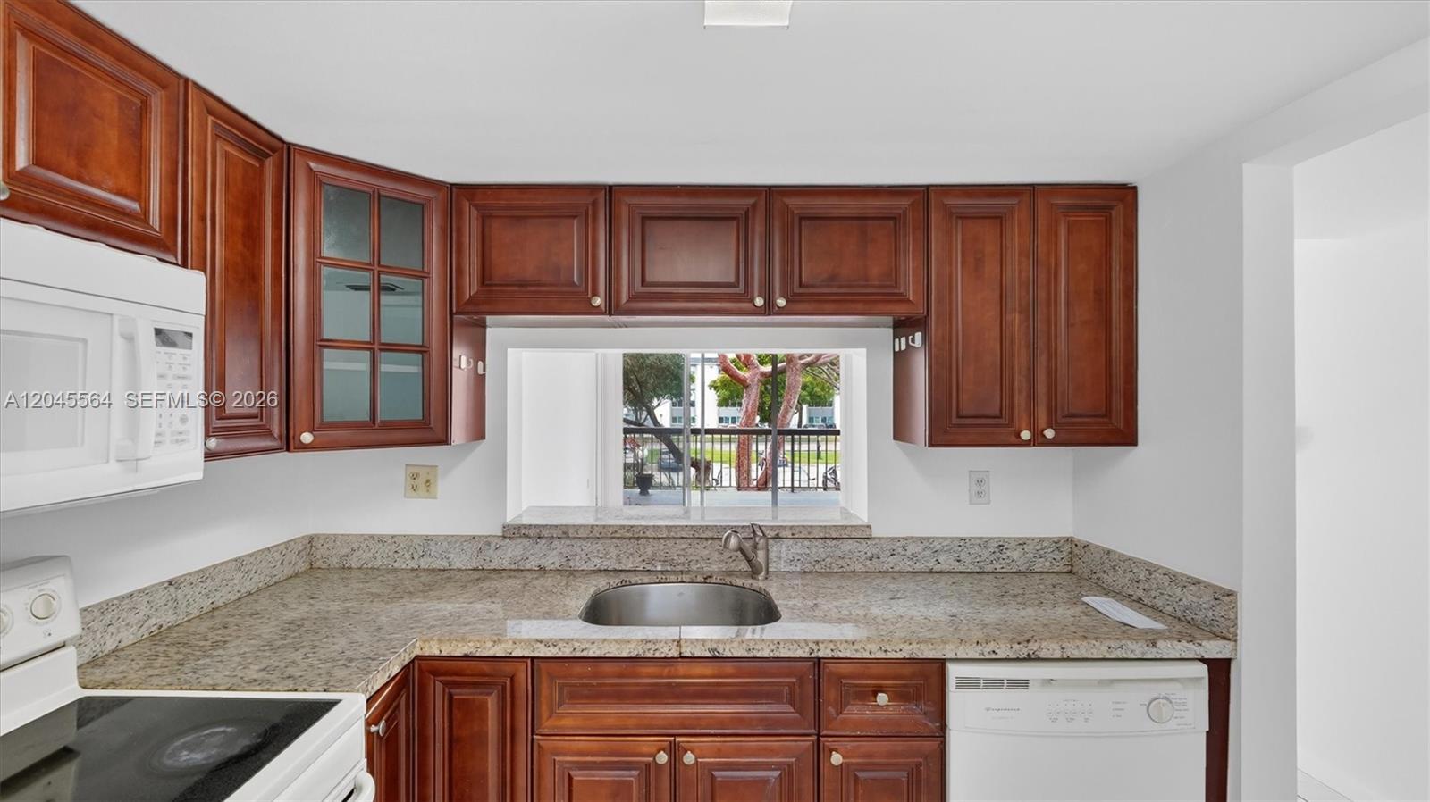 A kitchen features cherry wood cabinets, granite countertops, a stainless steel sink, and a window — 10975 SW 107th ST. # 202, Kendall FL 33176, KENDALL, FL