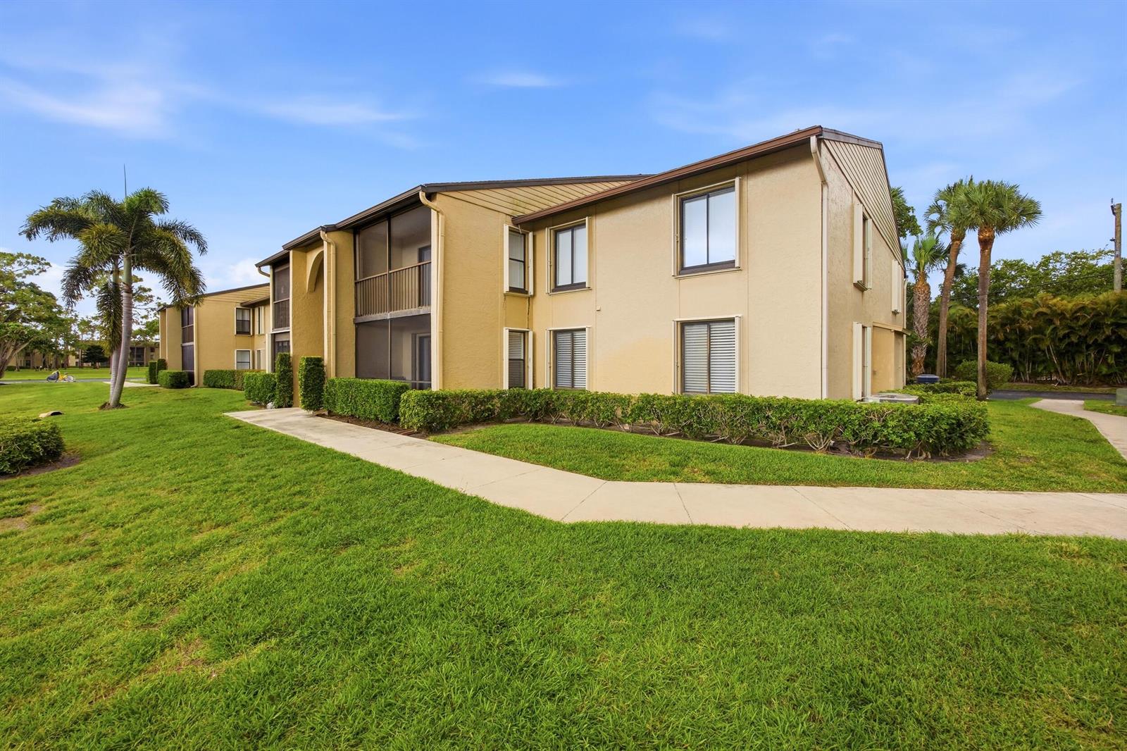 A two-story tan apartment building with a screened balcony and a concrete walkway — 722 Sunny Pine Way # B1, FL 33415, FL