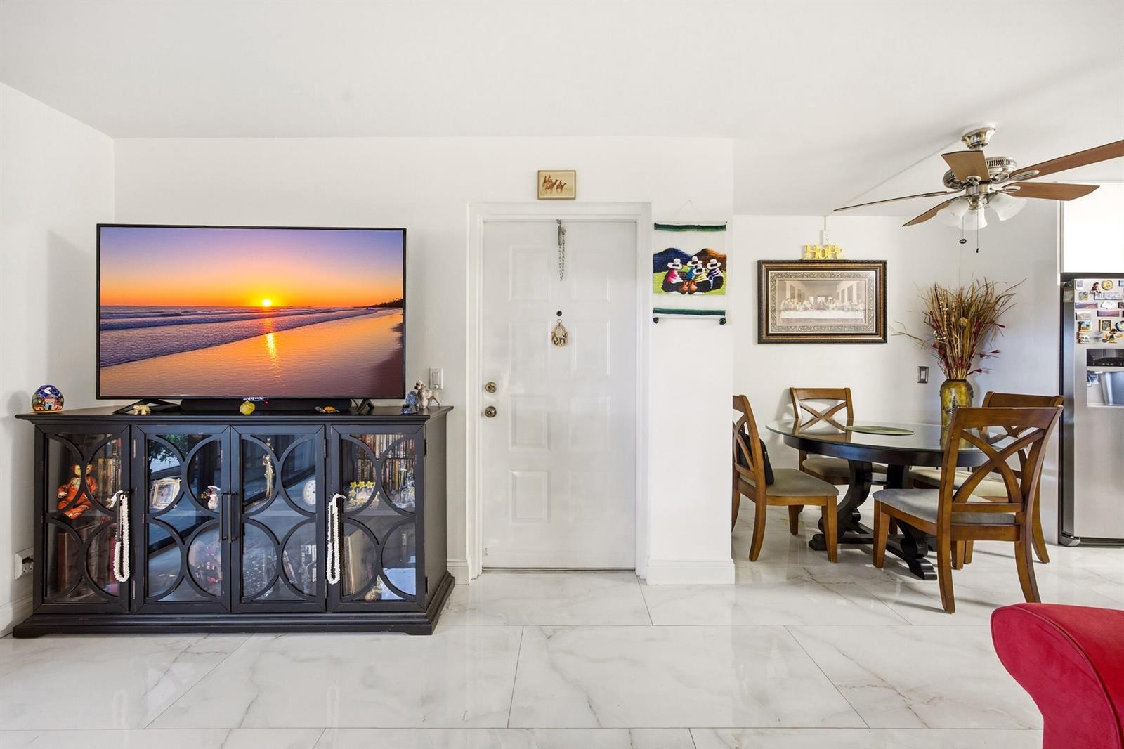 A living and dining area features white tile floors, a television console, and a dining set — 722 Sunny Pine Way # B1, FL 33415, FL