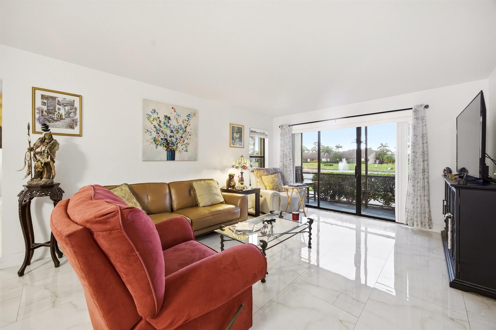 A living room with white tile floors, a leather sofa, red recliner, and sliding glass doors — 722 Sunny Pine Way # B1, FL 33415, FL