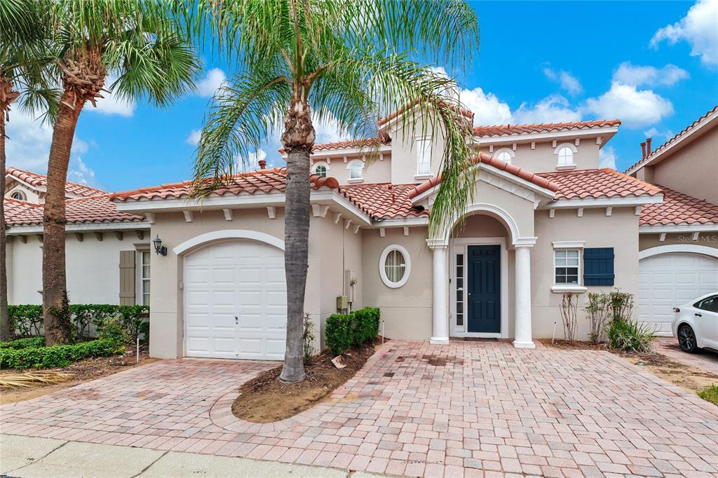 A two-story stucco house with a tile roof, a paved driveway, and a palm tree — 516 BRUNELLO DRIVE, DAVENPORT, FL
