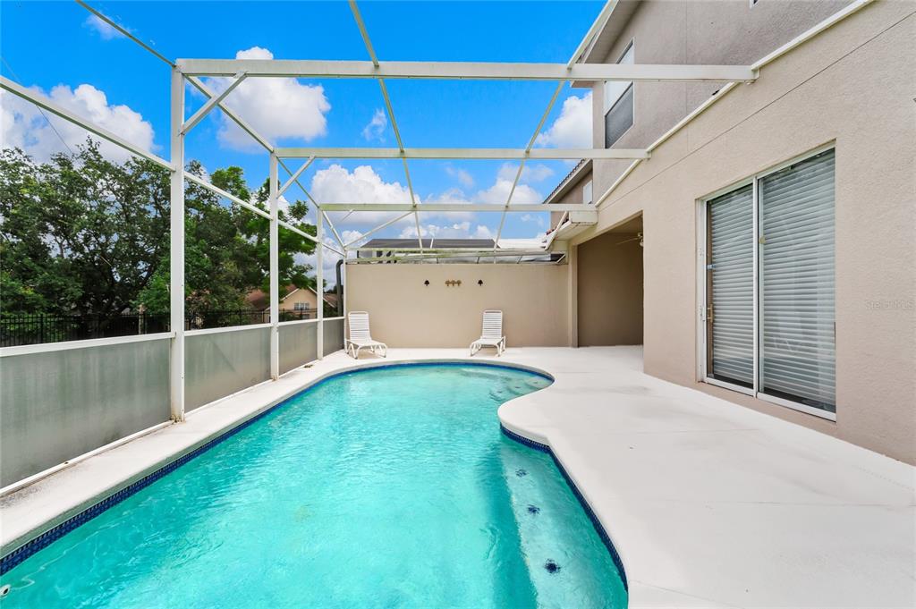 A swimming pool with a screened enclosure and two lounge chairs on a concrete patio — 516 BRUNELLO DRIVE, DAVENPORT, FL