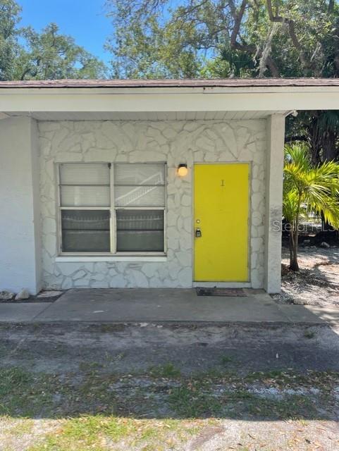 A single-story building exterior features a bright yellow door and a large window — 419 PINEAPPLE STREET UNIT 1, TARPON SPRINGS, FL