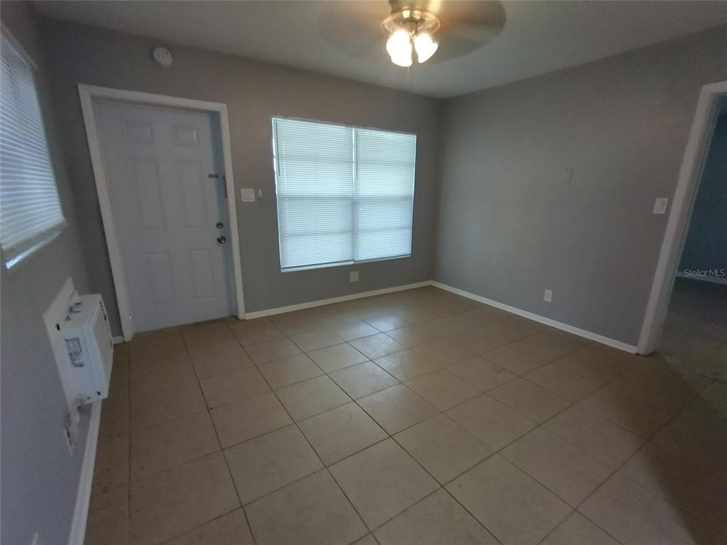 An empty room with light gray walls, tan tile flooring, a window, and a door — 419 PINEAPPLE STREET UNIT 1, TARPON SPRINGS, FL