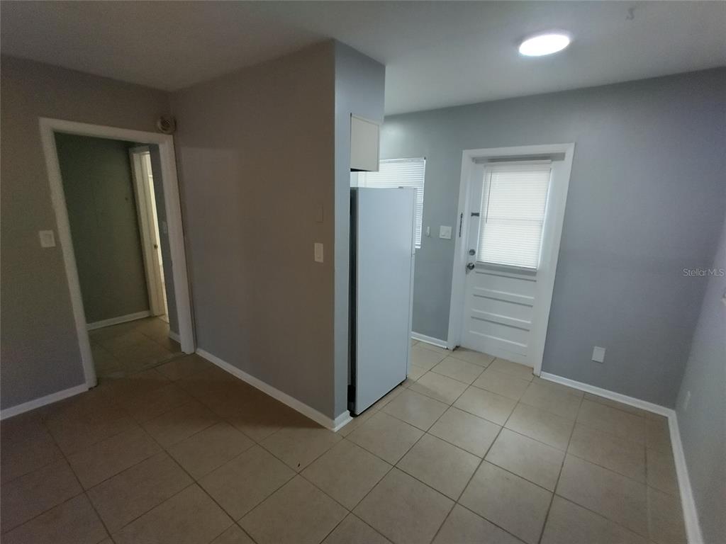 A kitchen area features light gray walls, tile flooring, a white refrigerator, and a back door — 419 PINEAPPLE STREET UNIT 1, TARPON SPRINGS, FL