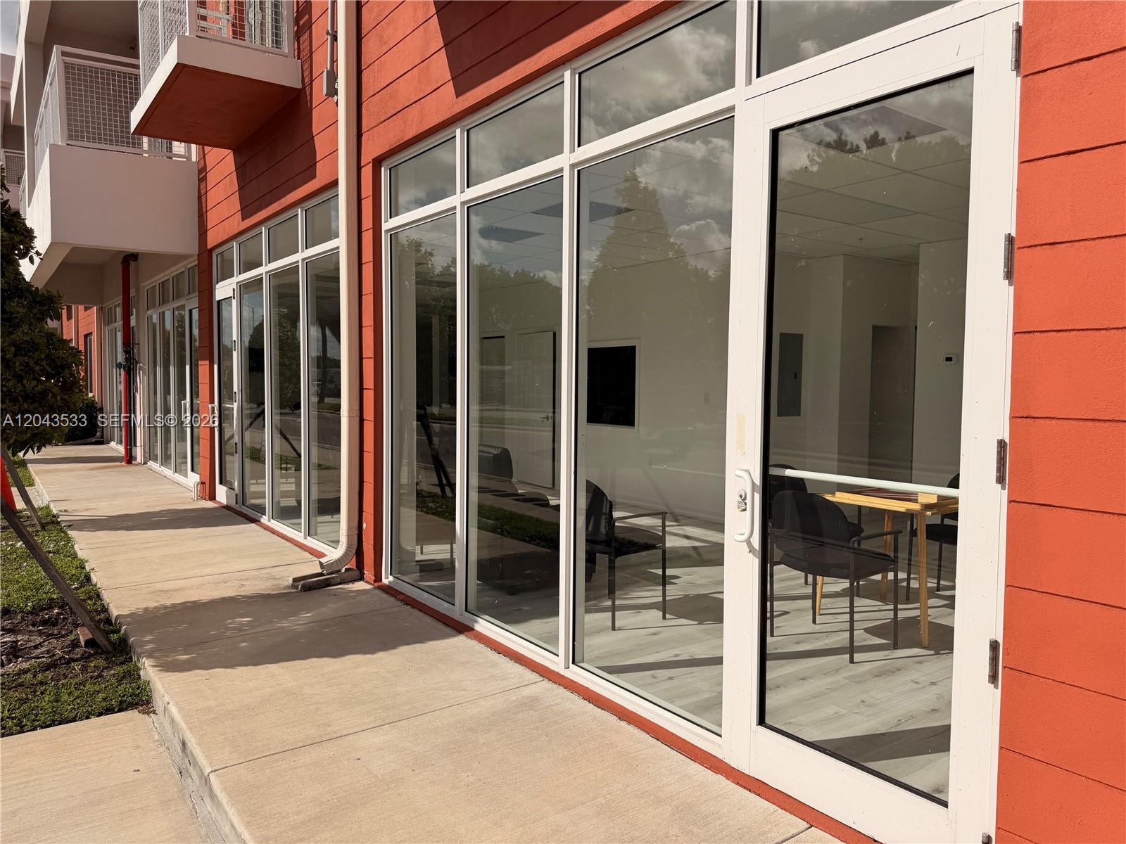 The exterior of a commercial building features orange walls, large glass windows, and a sidewalk — 665 E 49 ST, Hialeah FL 33013, HIALEAH, FL