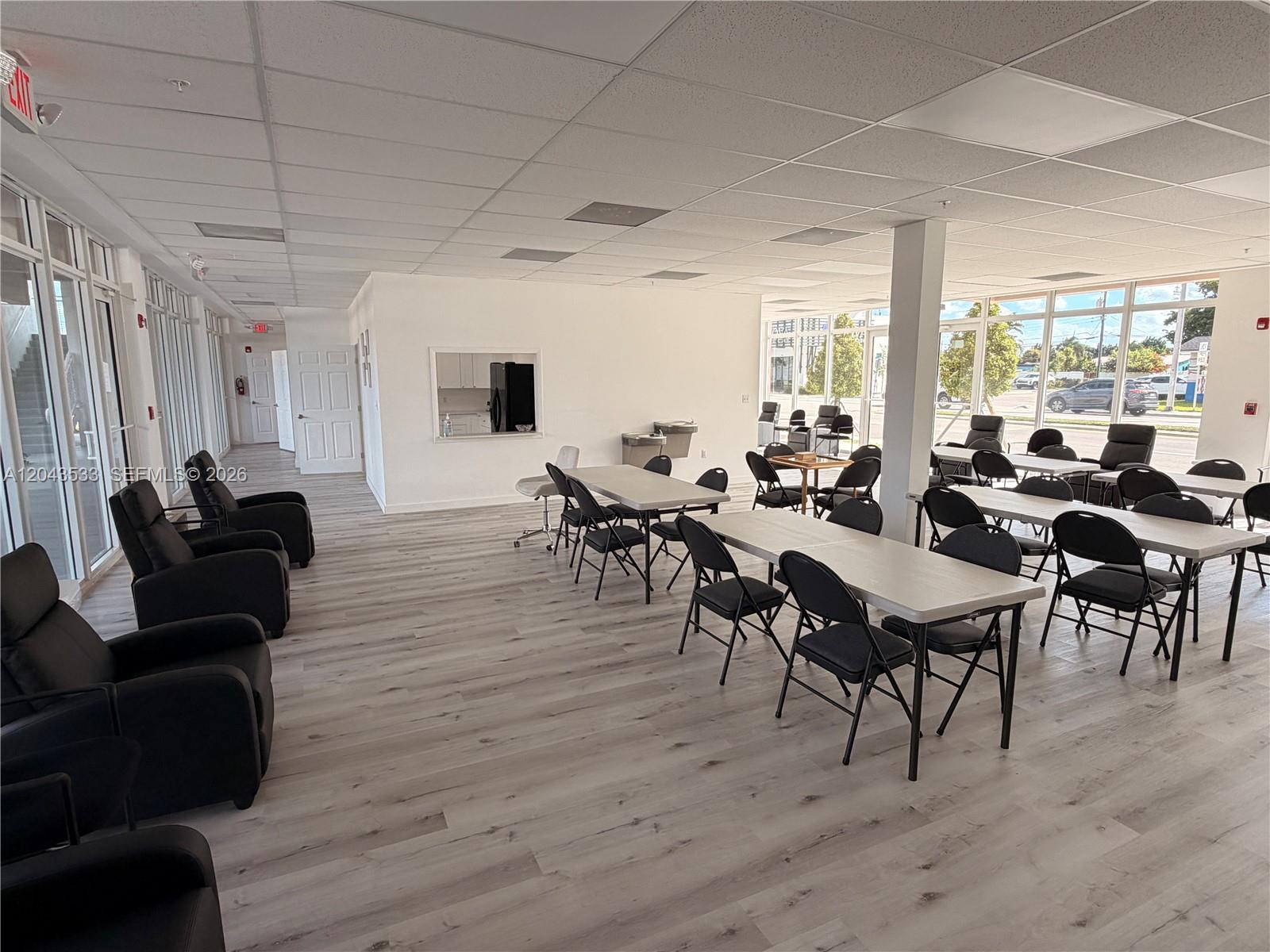 A bright, open-plan commercial space features light wood-look flooring, drop ceilings, and multiple tables and chairs — 665 E 49 ST, Hialeah FL 33013, HIALEAH, FL