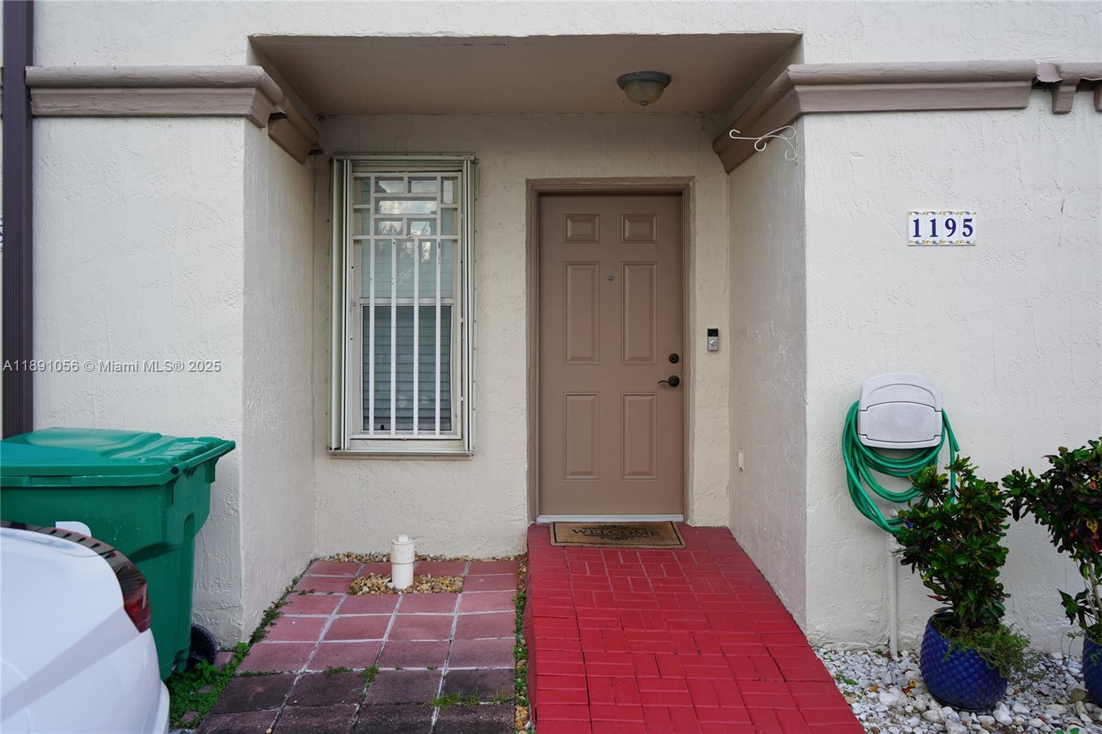 The exterior view shows a tan front door, a window with security bars, and a walkway — 1195 NW 124th Ave # 2202, Miami FL 33182, MIAMI, FL