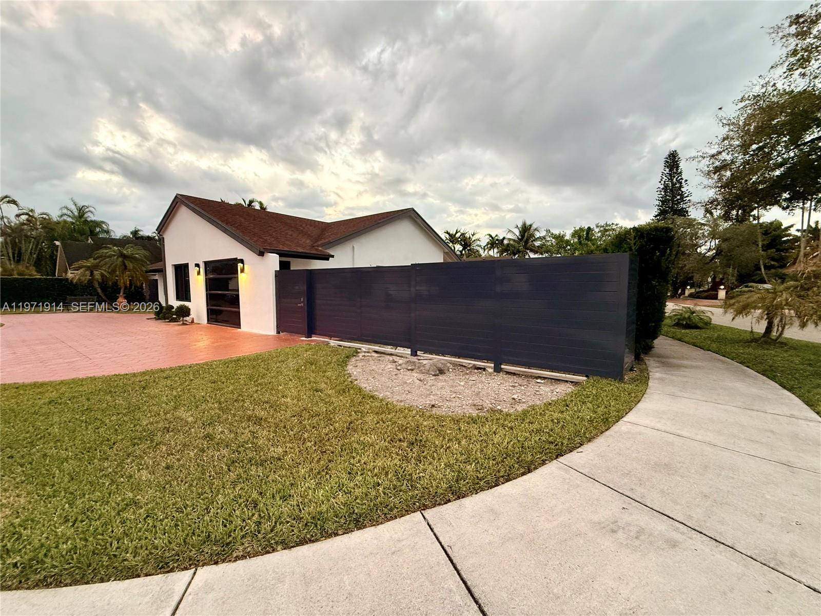 A white house with a dark horizontal fence and a red paved driveway — 13253 SW 96th Ter # 0, Miami FL 33186, MIAMI, FL