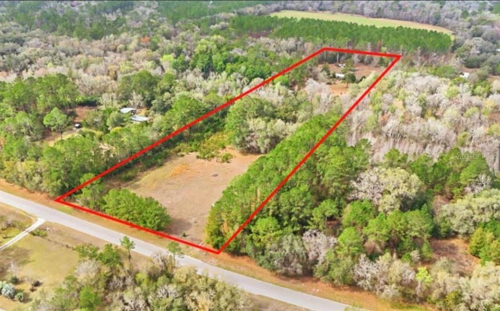 An aerial view shows a house and several outbuildings on a large, wooded rural lot — 17828 NE 21ST STREET, GAINESVILLE, FL