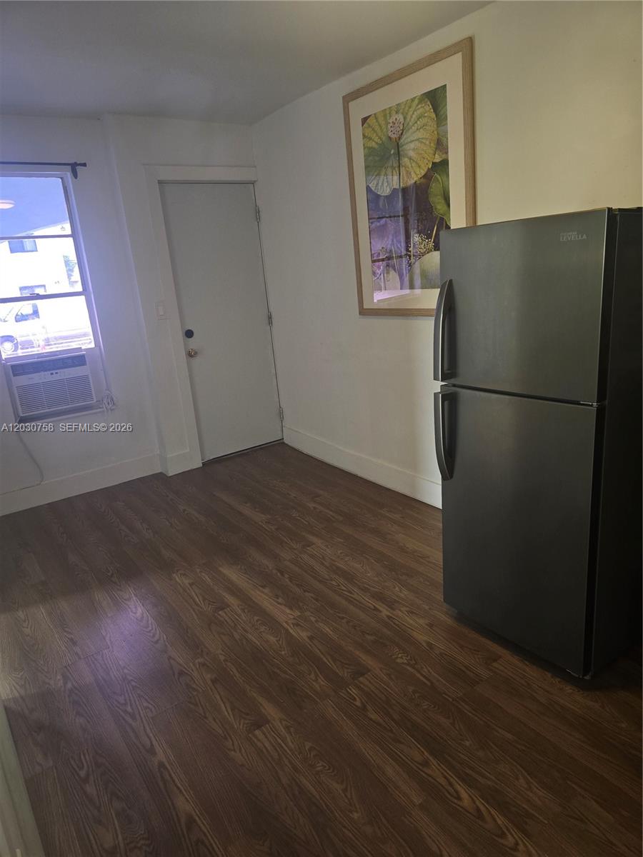 A room with wood-look flooring, a black refrigerator, a window air conditioner, and a door — 66 W 13th St # 3, Hialeah FL 33010, HIALEAH, FL