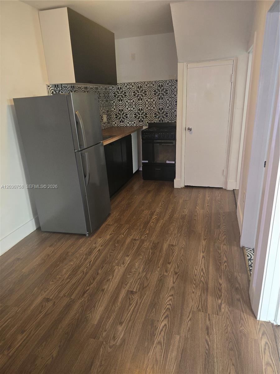 A small kitchen features a stainless steel refrigerator, black cabinets, and patterned backsplash tiles — 66 W 13th St # 3, Hialeah FL 33010, HIALEAH, FL