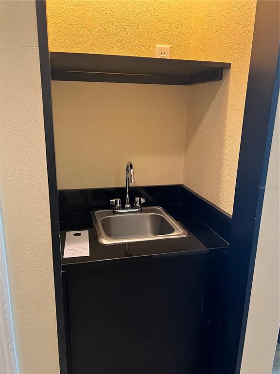 A small wet bar area features a stainless steel sink, black countertop, and overhead shelf — 3000 MAINGATE LANE UNIT 218, KISSIMMEE, FL