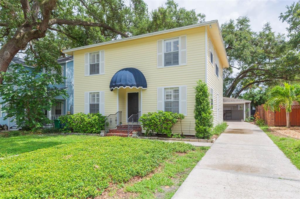 A two-story yellow house with a dark blue awning over the front entrance and driveway — 4210 W ROLAND STREET, TAMPA, FL