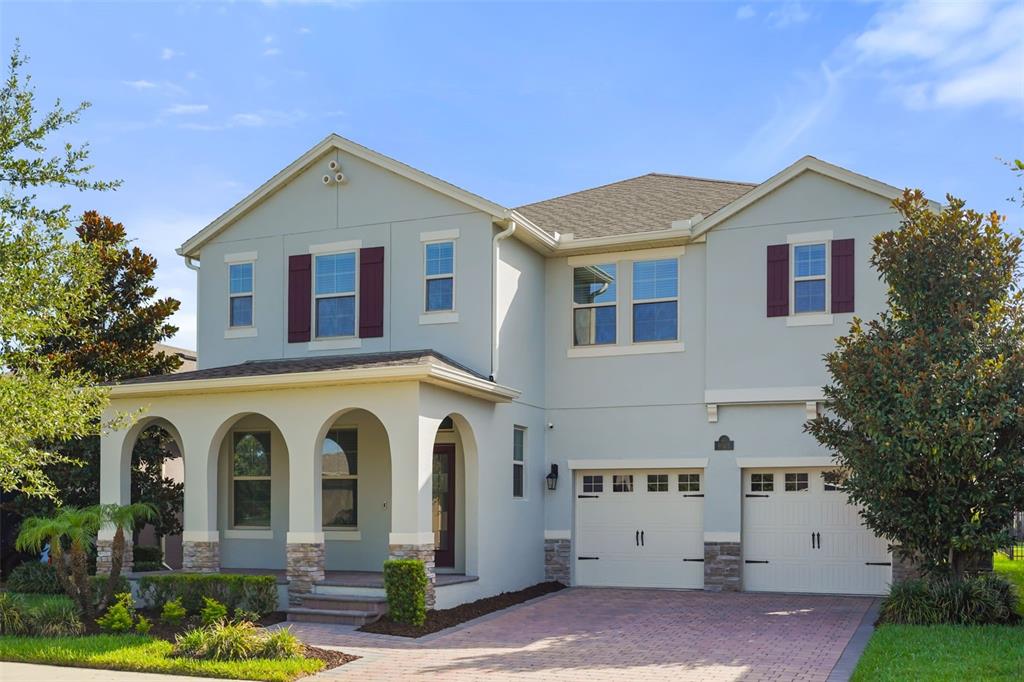 A two-story house with a light-colored stucco exterior, arched front porch, and two-car garage — 9561 WATERWAY PASSAGE DRIVE, WINTER GARDEN, FL