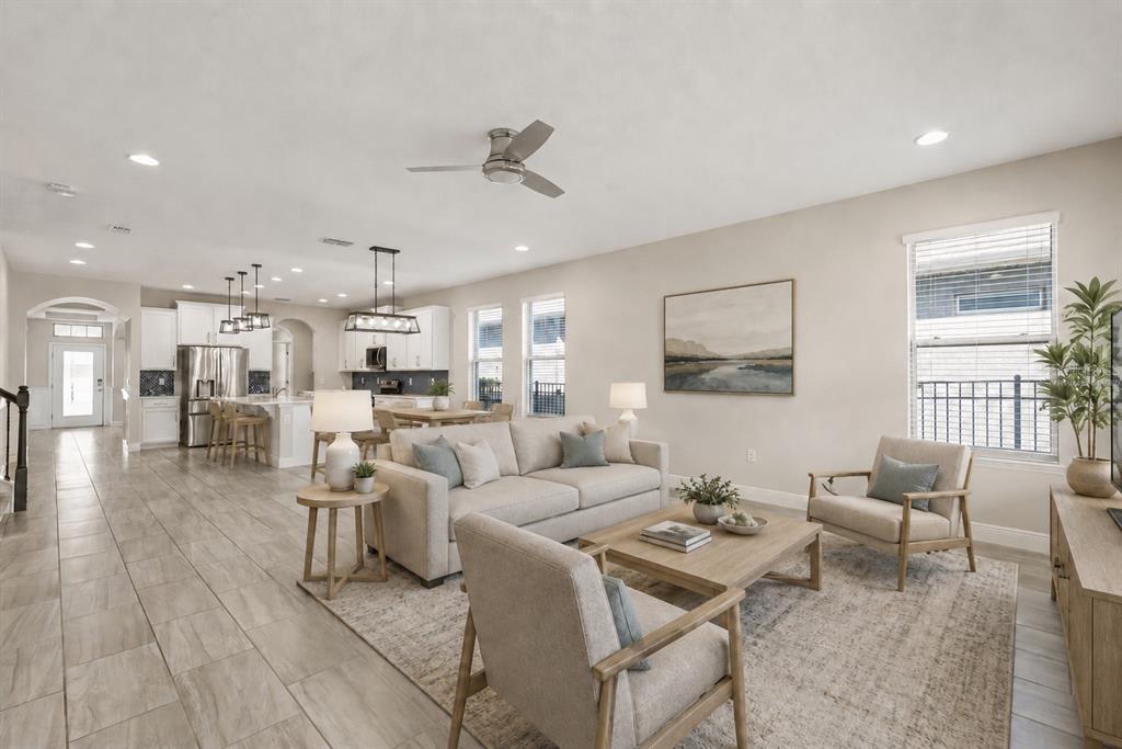 A bright, open-concept living room features neutral furniture, tile flooring, and an adjoining kitchen — 9561 WATERWAY PASSAGE DRIVE, WINTER GARDEN, FL
