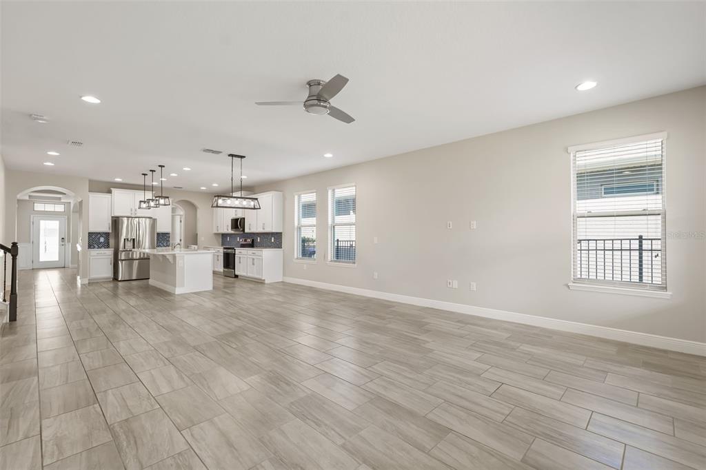 An open-concept kitchen and living area features light wood-look tile flooring and white cabinetry — 9561 WATERWAY PASSAGE DRIVE, WINTER GARDEN, FL