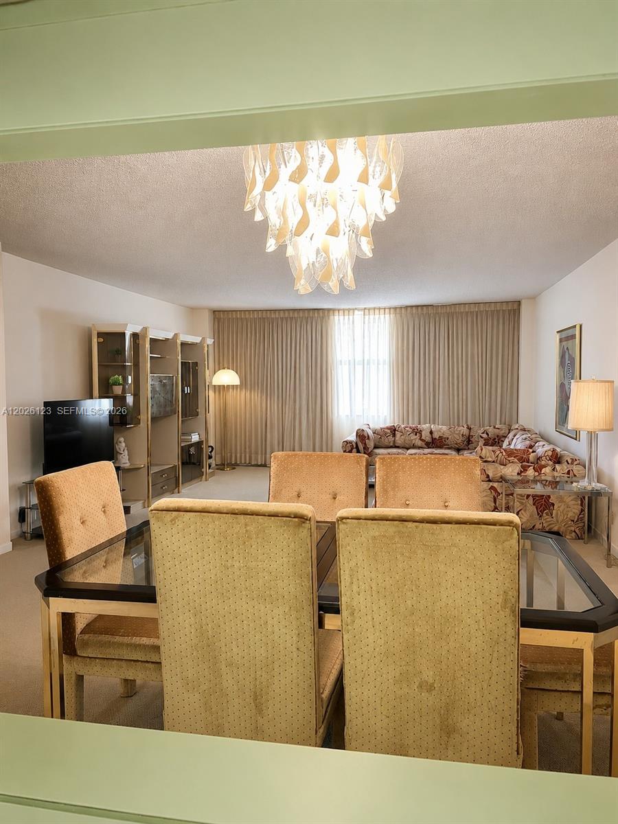 A dining area with a glass-topped table leads into a living room with patterned furniture — 1865 S Ocean Dr # 2G, Hallandale Beach FL 33009, HALLANDALE BEACH, FL