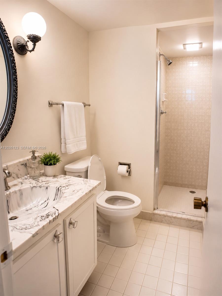 A bathroom features a marble-topped vanity, a white toilet, and a tiled walk-in shower — 1865 S Ocean Dr # 2G, Hallandale Beach FL 33009, HALLANDALE BEACH, FL