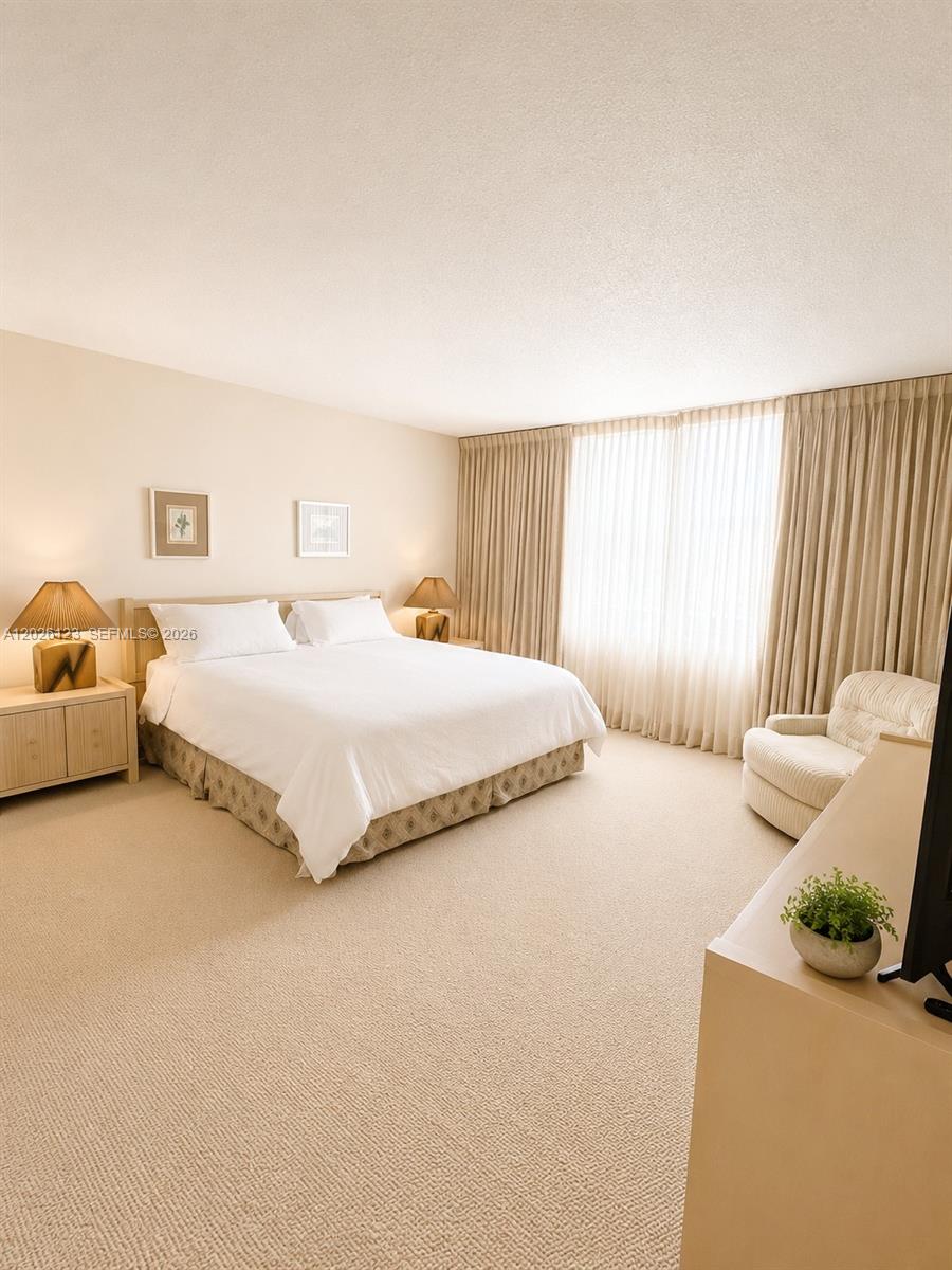 A bedroom features a king bed, two nightstands with lamps, and a beige armchair — 1865 S Ocean Dr # 2G, Hallandale Beach FL 33009, HALLANDALE BEACH, FL