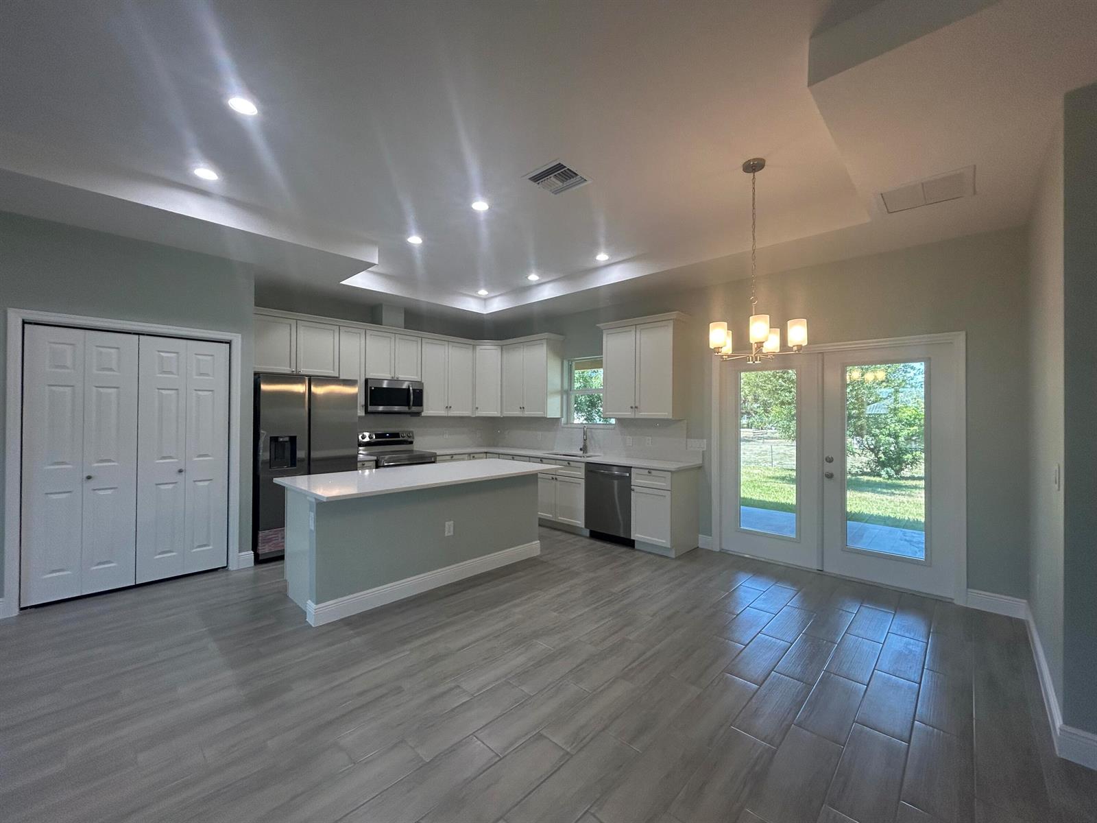 A kitchen with white cabinets, stainless steel appliances, a center island, and light-colored tile flooring — 3935 NW 18th Avenue, Okeechobee FL 34972, OKEECHOBEE, FL