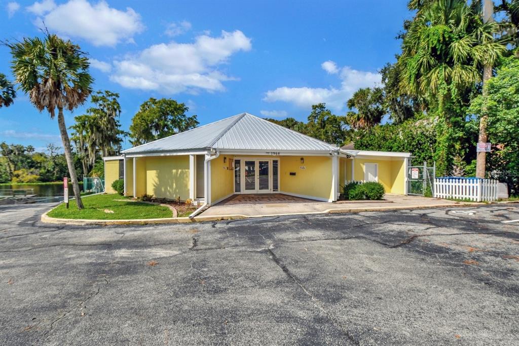 A yellow, single-story building with a metal roof sits beside a lake and parking lot — 2701 KINGFISHER VILLAGE, DELAND, FL