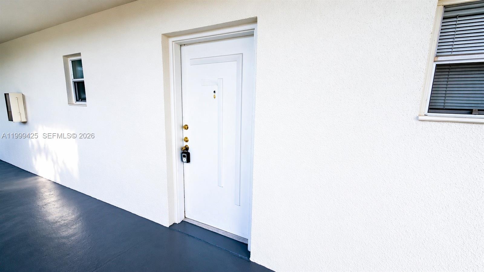A white exterior door with a lockbox is centered on a plain stucco wall — 4255 N University Dr # 308, Sunrise FL 33351, SUNRISE, FL