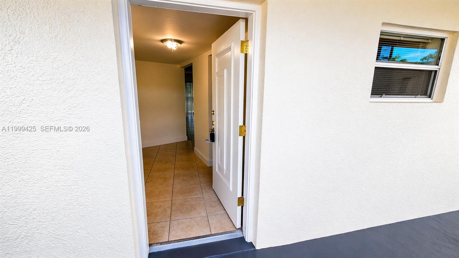 An open white door reveals a tiled interior hallway with a ceiling light fixture — 4255 N University Dr # 308, Sunrise FL 33351, SUNRISE, FL