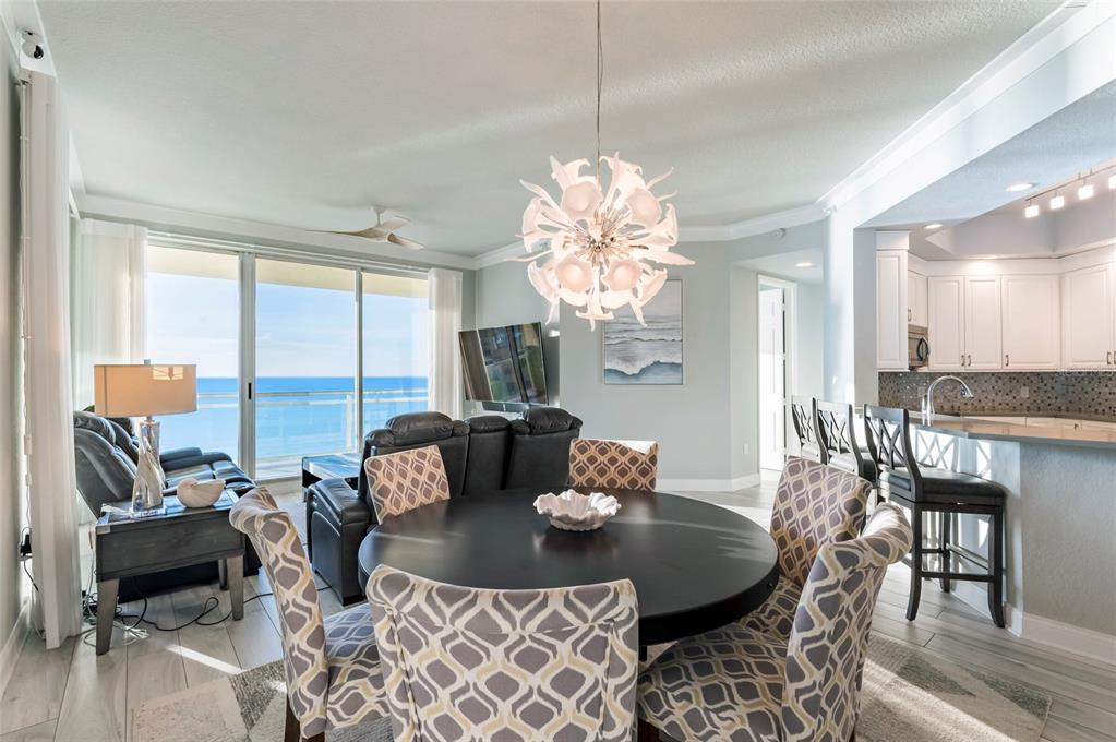 A dining area with a round table and patterned chairs overlooks a balcony and ocean — 1170 GULF BOULEVARD UNIT 2203, CLEARWATER BEACH, FL