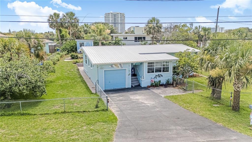 A light blue single-story house features a metal roof, a garage, and a paved driveway — 1420 N GRANDVIEW AVENUE, DAYTONA BEACH, FL