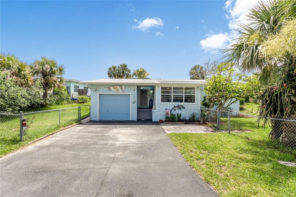 A single-story light blue house with a garage and a paved driveway under a blue sky — 1420 N GRANDVIEW AVENUE, DAYTONA BEACH, FL
