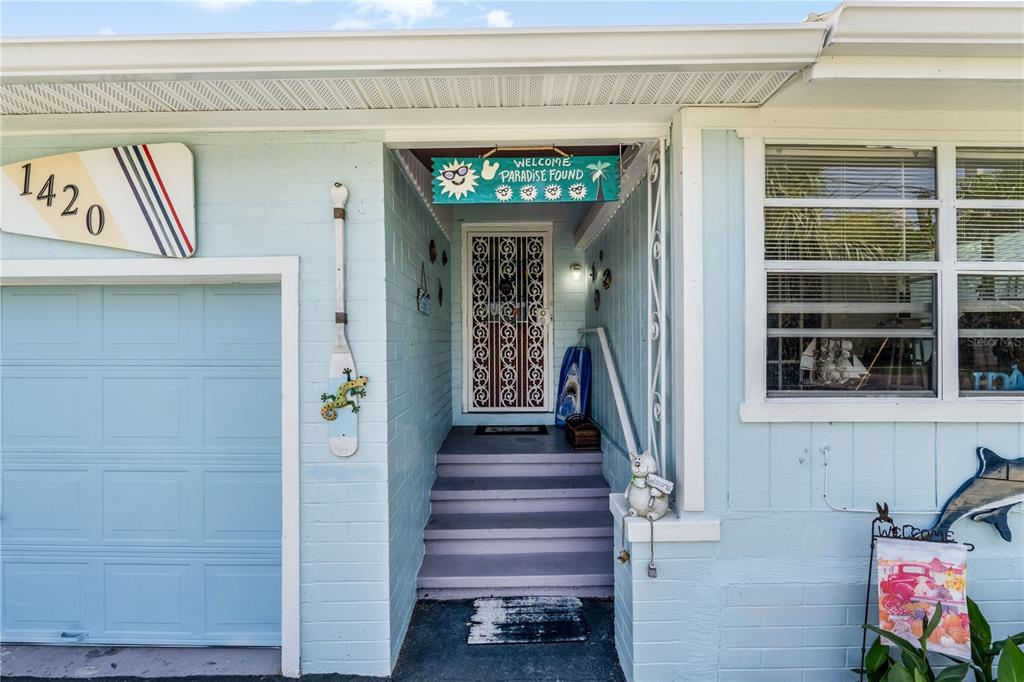 The exterior of a light blue house features a front entrance with steps and decor — 1420 N GRANDVIEW AVENUE, DAYTONA BEACH, FL