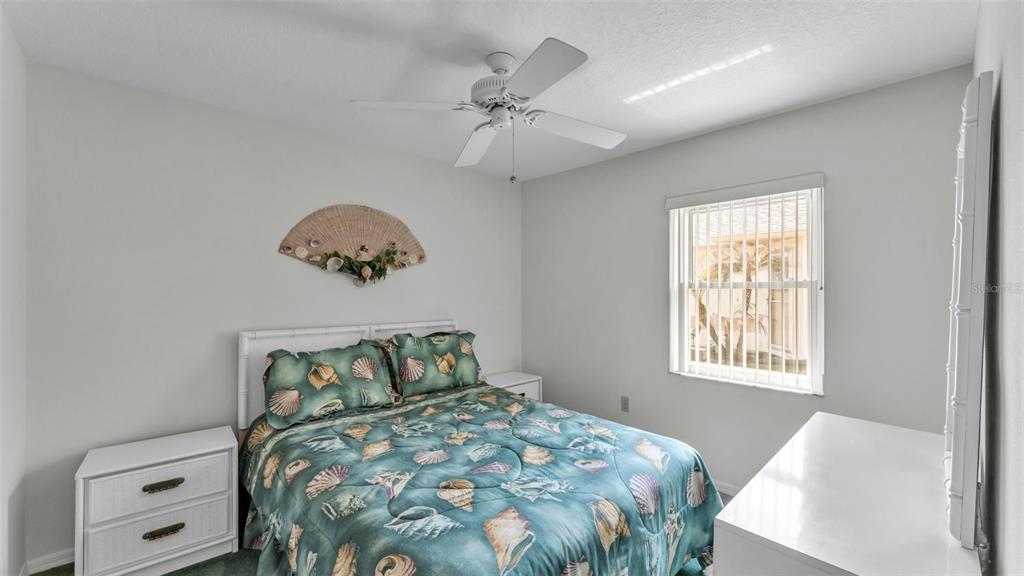 A bedroom features a bed with a seashell-patterned comforter, white furniture, and a ceiling fan — 6236 RAVEN RUN, LAKELAND, FL