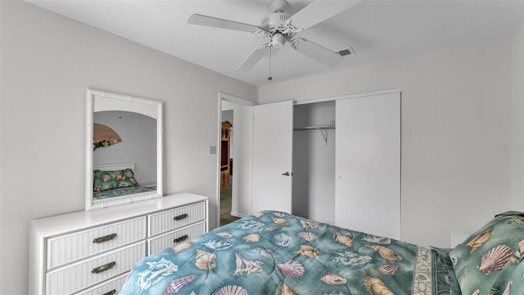 A bedroom features a white dresser with a mirror, a ceiling fan, and a closet — 6236 RAVEN RUN, LAKELAND, FL