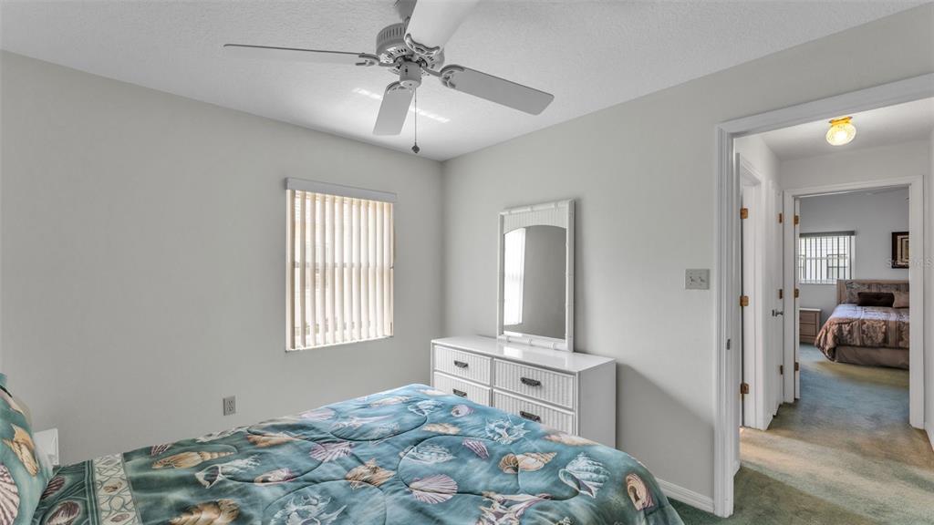 A bedroom features a shell-patterned bedspread, a white dresser with a mirror, and a ceiling fan — 6236 RAVEN RUN, LAKELAND, FL