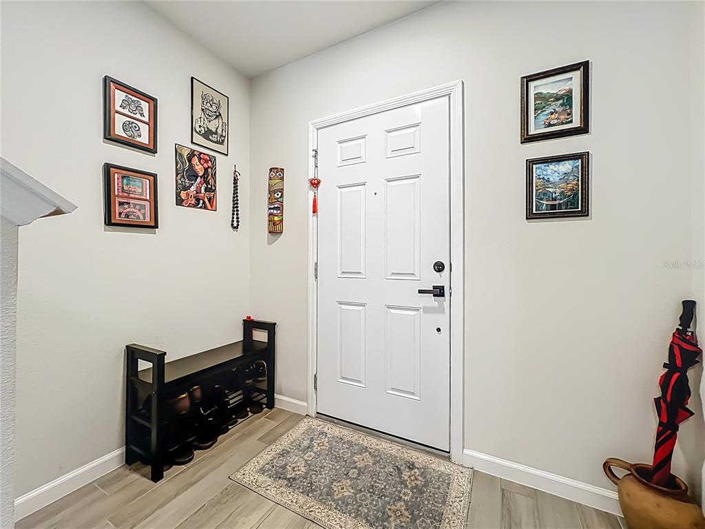 An entryway features a white door, a shoe rack, wall art, and a patterned rug — 4460 CAMPSITE LOOP, ORLANDO, FL