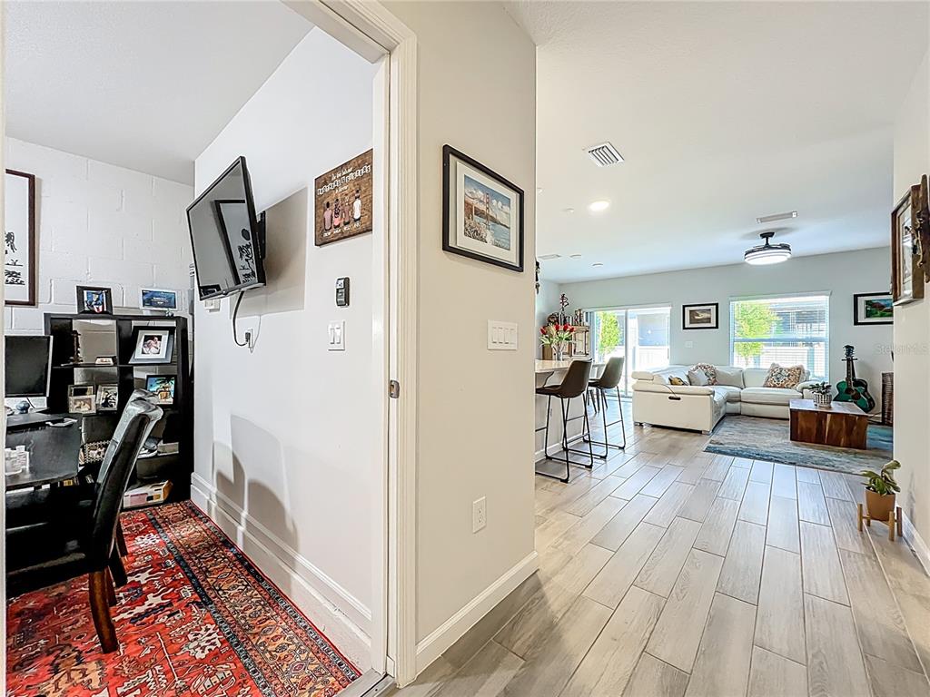 A view from a home office into an open-concept living room with tile flooring — 4460 CAMPSITE LOOP, ORLANDO, FL