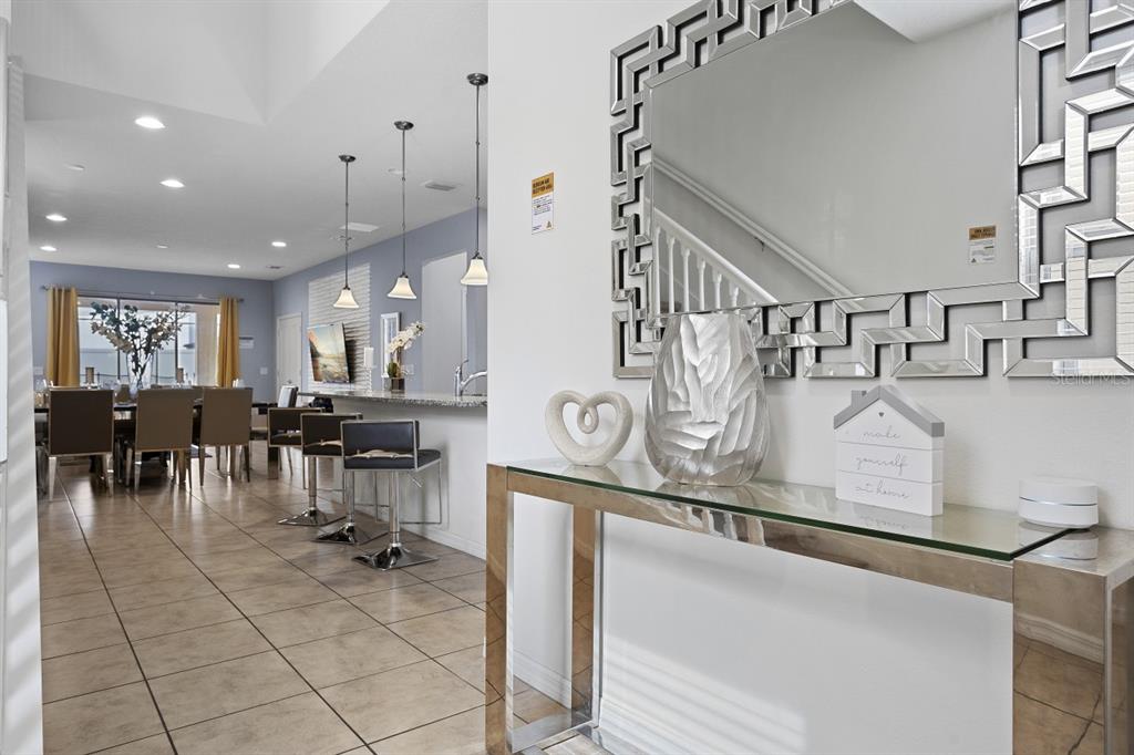A foyer with a glass console table leads to an open-concept kitchen and dining area — 1724 LIMA AVE, KISSIMMEE, FL