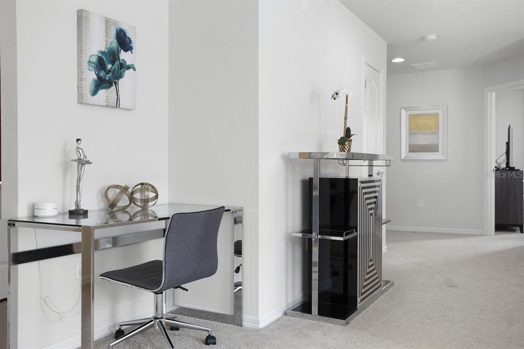 A modern home office area features a glass desk, a gray chair, and a bar cabinet — 1724 LIMA AVE, KISSIMMEE, FL