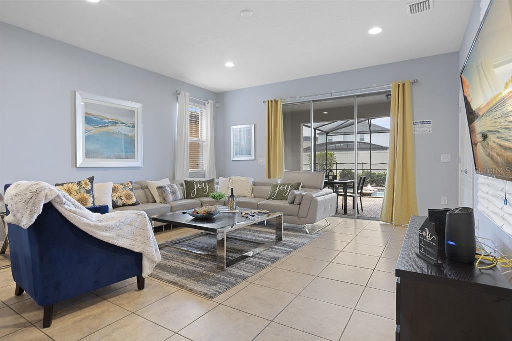 A living room features a sectional sofa, blue armchair, coffee table, and sliding glass doors — 1724 LIMA AVE, KISSIMMEE, FL
