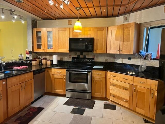 A kitchen features light wood cabinets, black countertops, stainless steel appliances, and a wood-paneled ceiling — 600 Uno Lago Dr # 302, Juno Beach FL 33408, JUNO BEACH, FL