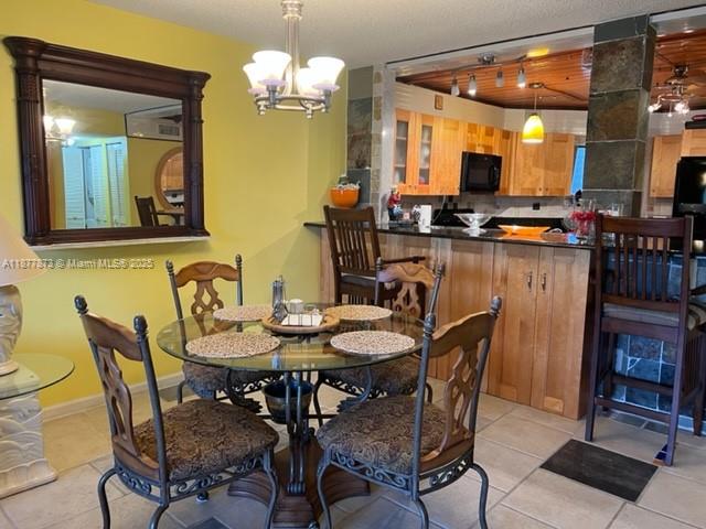 A dining area with a glass table, chairs, and a kitchen counter in the background — 600 Uno Lago Dr # 302, Juno Beach FL 33408, JUNO BEACH, FL