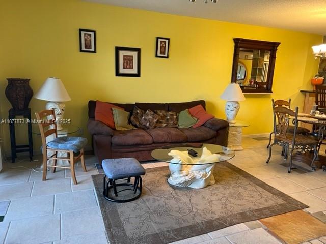 A living room features a brown sofa, a glass coffee table, and bright yellow walls — 600 Uno Lago Dr # 302, Juno Beach FL 33408, JUNO BEACH, FL