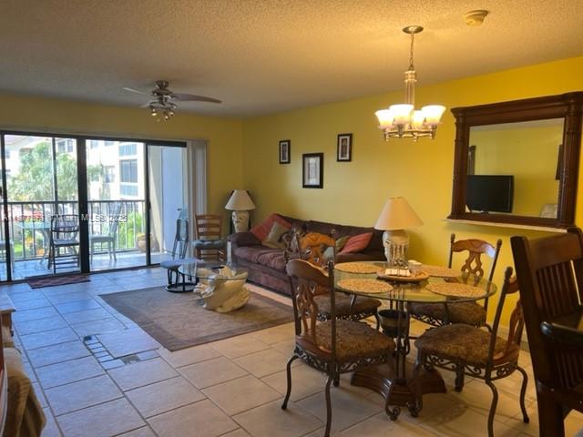 A living and dining area features yellow walls, tile floors, and a sliding glass door — 600 Uno Lago Dr # 302, Juno Beach FL 33408, JUNO BEACH, FL