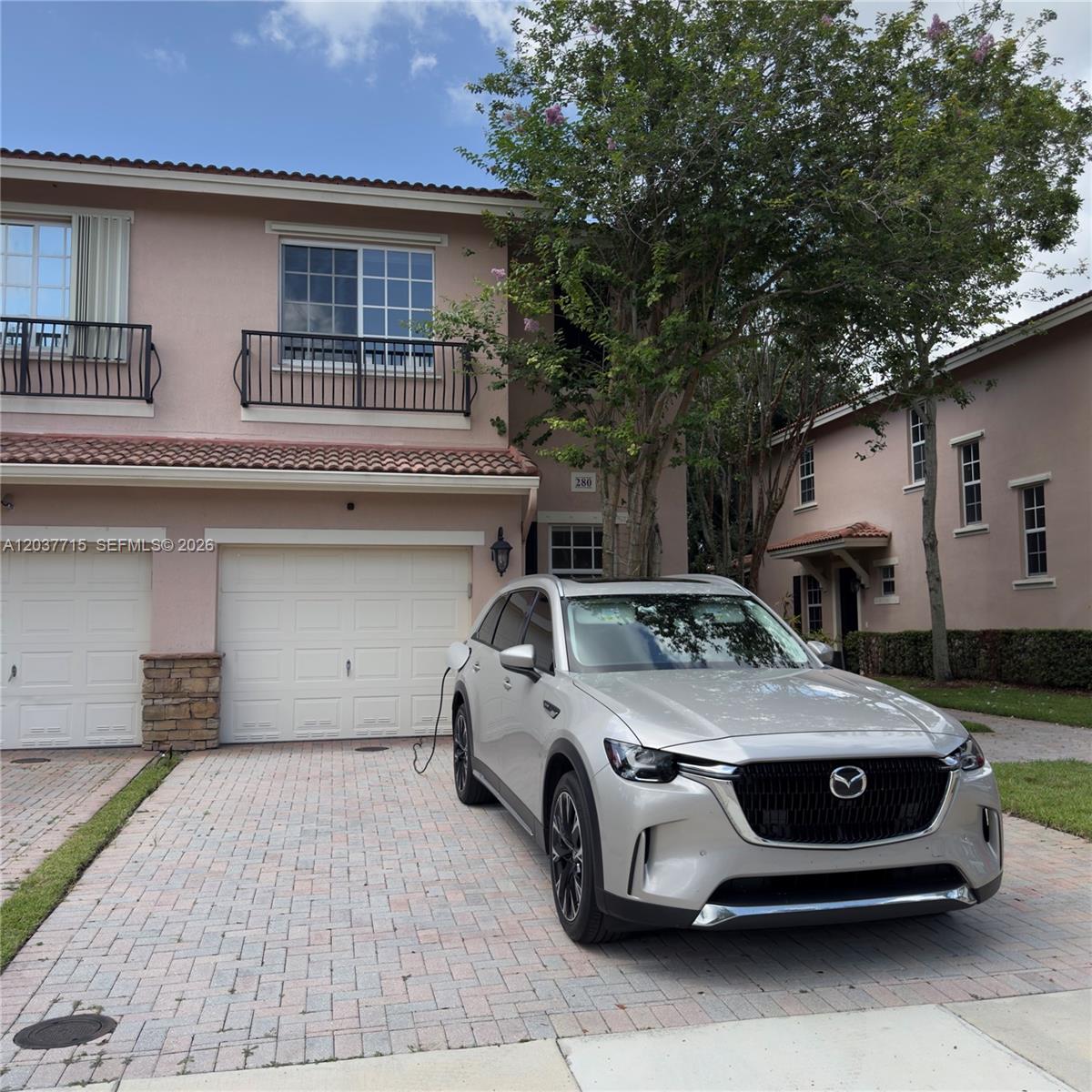A silver Mazda SUV is parked in the driveway of a two-story pink townhouse — 280 Las Brisas Cir # 280, Sunrise FL 33326, SUNRISE, FL