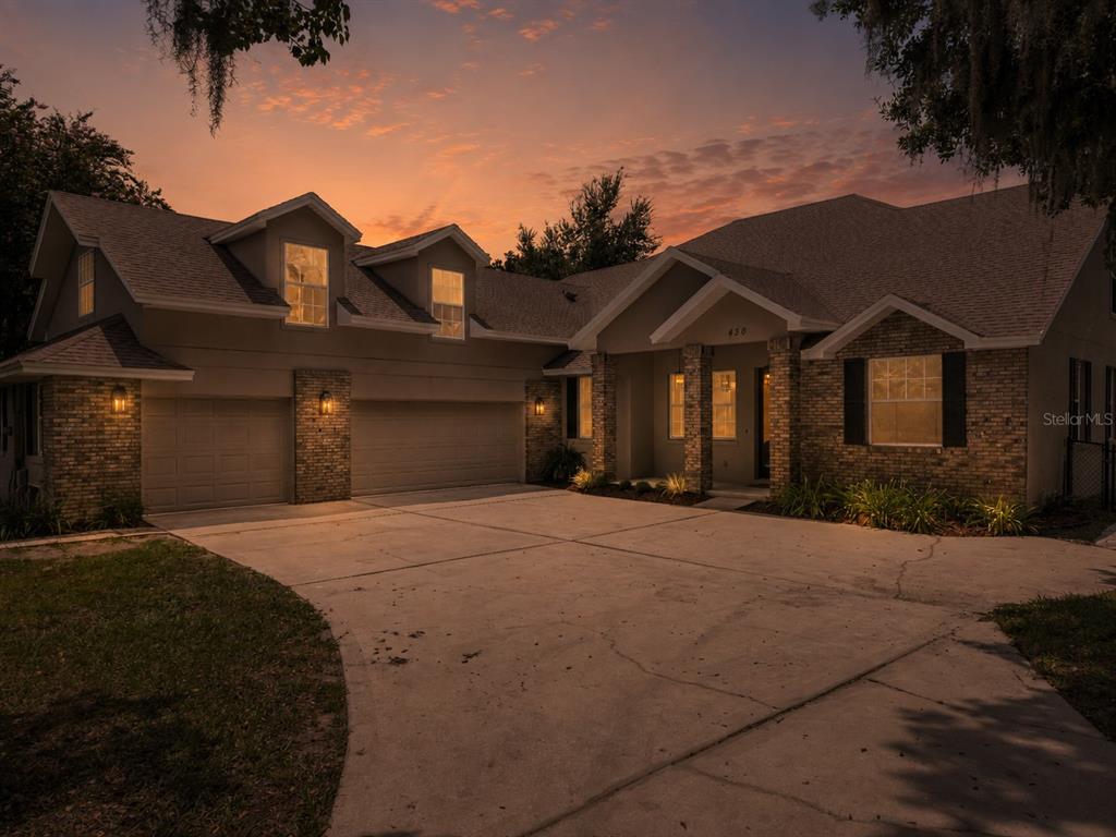 A two-story brick and stucco house with a multi-car garage at sunset — 430 BYWATER DRIVE, ORLANDO, FL
